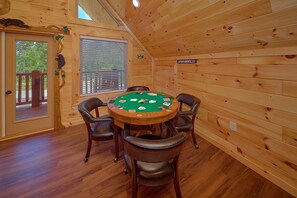 A wooden cabin interior with a poker table, chairs, and a sign indicating a play area. - Amazing Mountain Cabin Rental (Sevierville)
