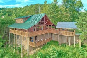 A wooden cabin with a balcony, elevated structure, and a separate building with a sloped roof. - Timberwolf | Smoky Mtn Views, Hot Tub, Game Room, King Suites, Fireplace + Free Attraction Tickets (Wears Valley)