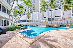 A swimming pool with lounge chairs and palm trees.