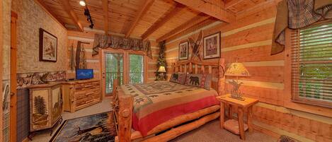 A log cabin interior with a bed, a desk, and a fireplace.