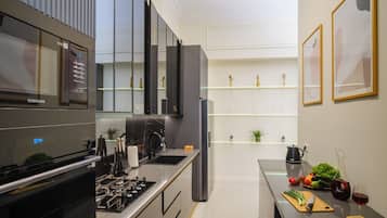 A modern kitchen with a built-in oven, a stainless steel sink, and a countertop with a kettle and a wine glass.