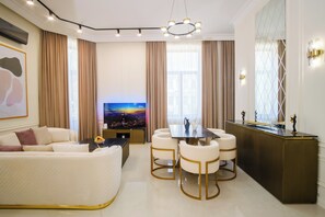 Een moderne woonkamer met een bank, een eettafel met stoelen, een televisie en een decorrek.