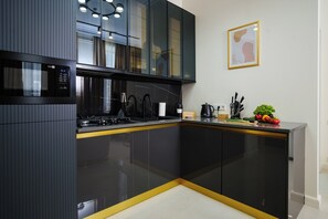 Een moderne keuken met zwarte kastjes, een ingebouwde magnetron en een roestvrijstalen afzuigkap.
