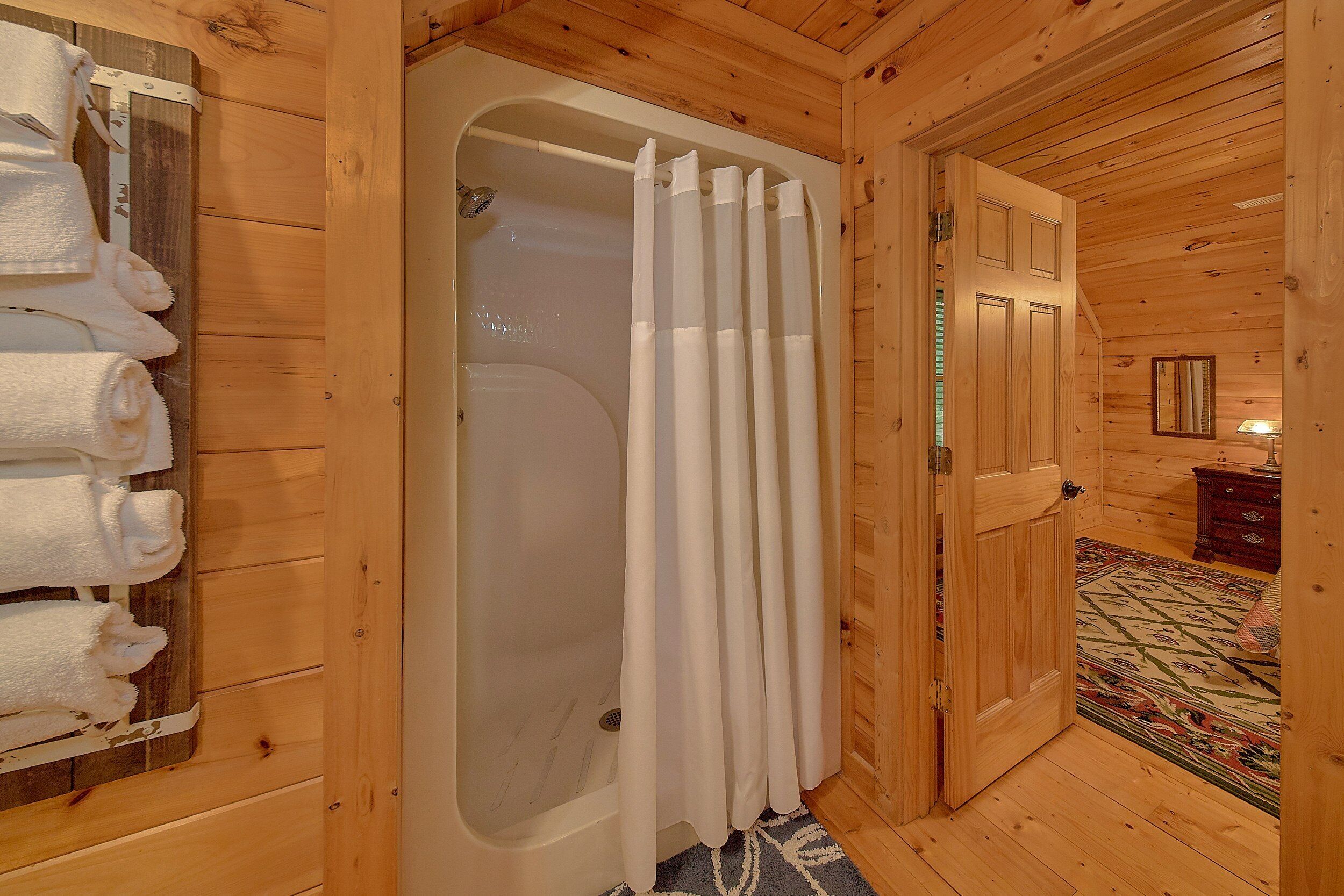 A wooden interior with a bathtub, a door, and a mirror.