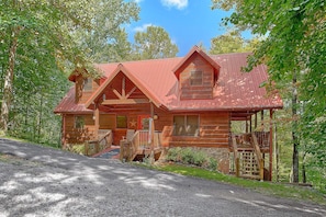 A wooden cabin with a red roof, a porch, and a staircase leading to the entrance. - Moonlight Magic | Hot Tub, Resort Pool, Fireplace + Free Attraction Tickets (Wears Valley)