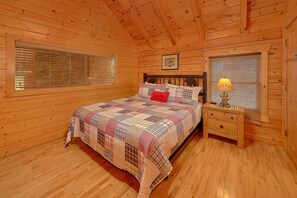 Een slaapkamer in een houten chalet, met een bed, nachtkastje en jaloezieën.