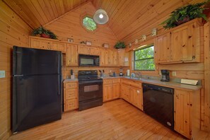 Cocina de cabaña de madera con refrigerador, estufa, microondas, pileta y lavavajillas.
