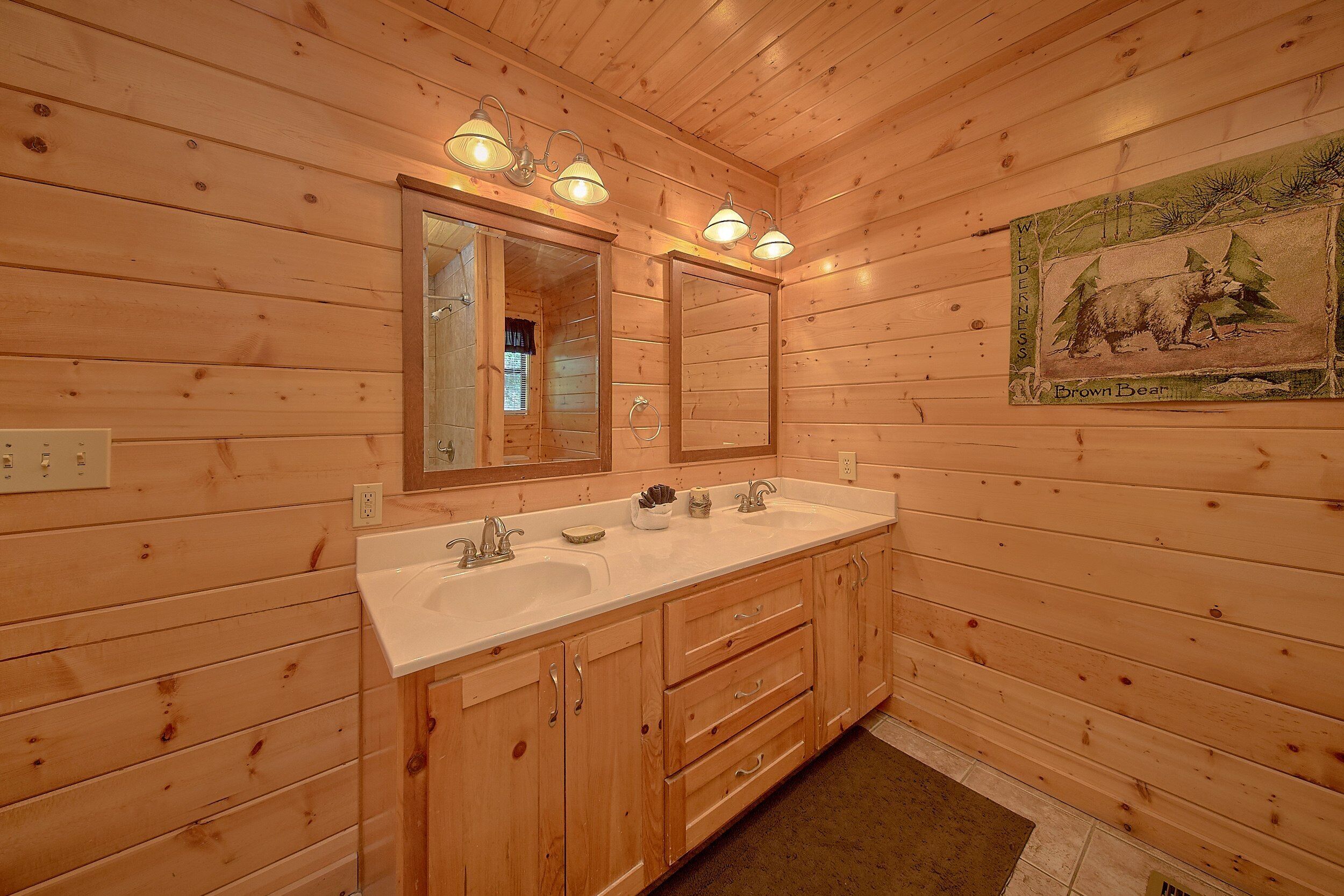 A wooden cabin bathroom with a double sink, vanity, and a mirror.