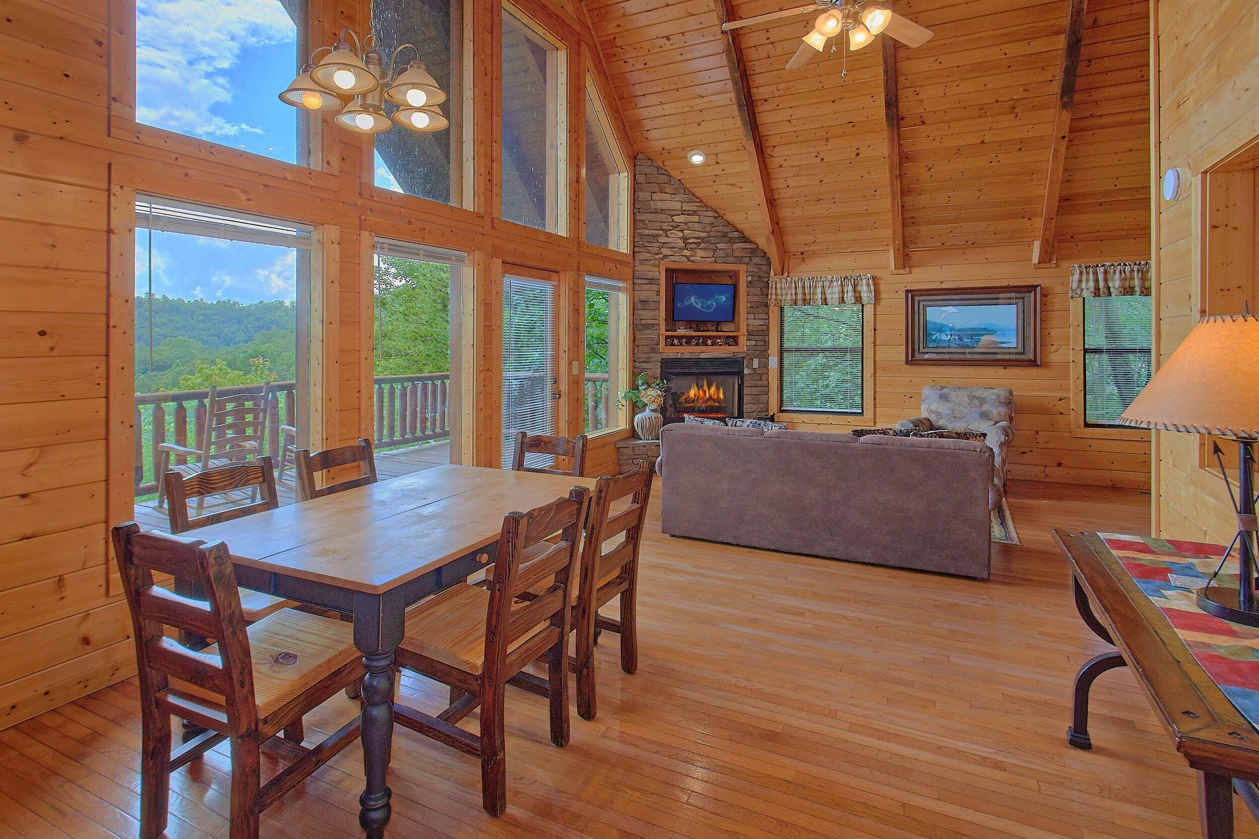 A wooden interior with a dining table, chairs, a sofa, and a fireplace.