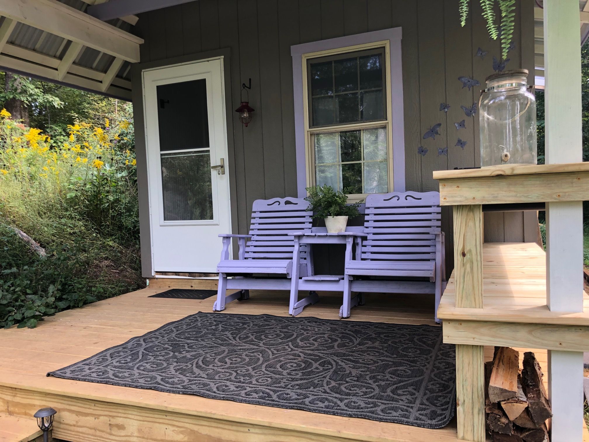 Eine Veranda mit einer Bank, einem kleinen Tisch und einem Blumentopf.