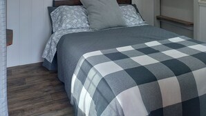 Ein Schlafzimmer mit einem Bett, einem großen Gemälde mit Waldmotiv und einer Holzbalkendecke.