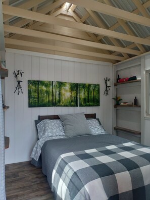 A bedroom with a bed, a large forest-themed painting, and a wooden ceiling. - Butterfly Camp near Old Rag Mountain and Shenandoah National Park (Etlan)