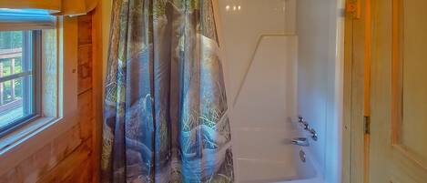 Ein Badezimmer mit Dusche, Toilette und Fenster.