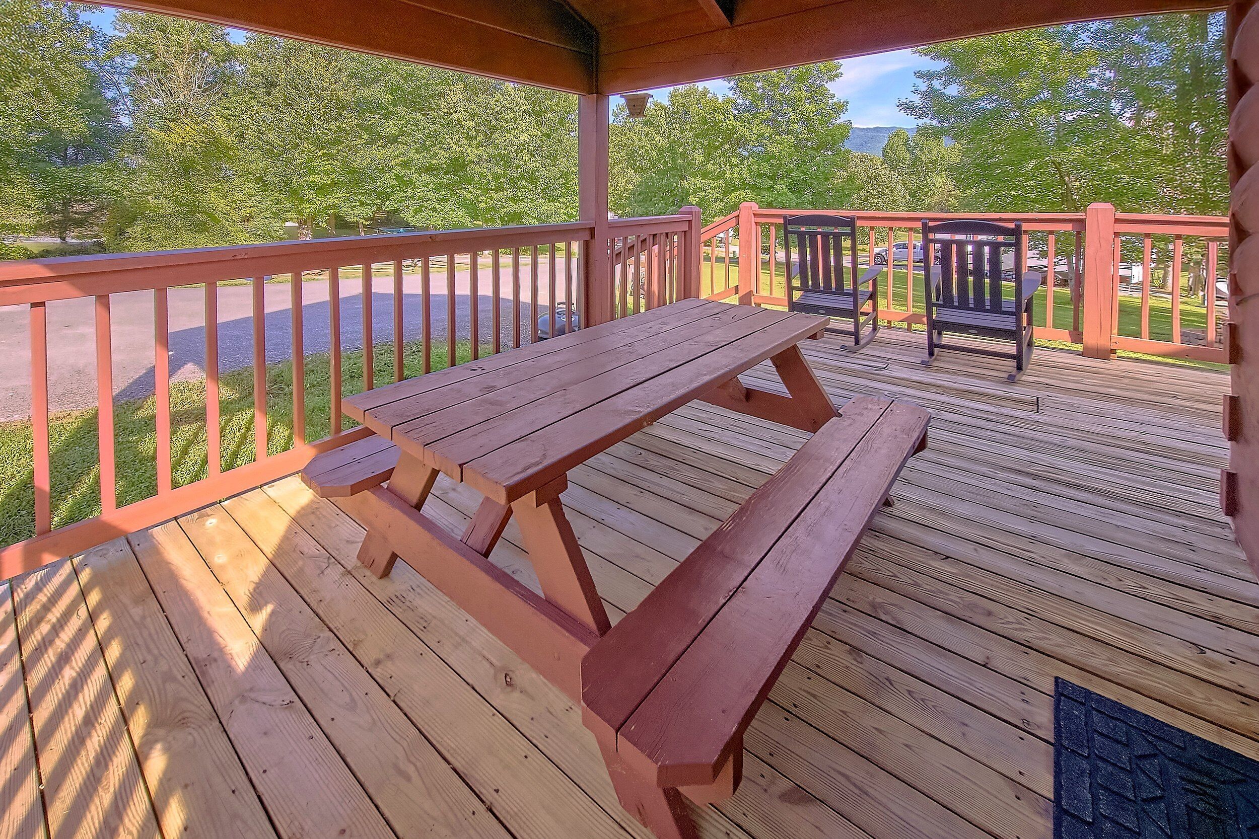 Eine Holzterrasse mit Picknicktischen und Bänken, umgeben von einer Brüstung.