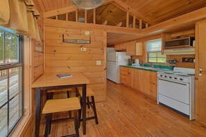 A wooden cabin with a kitchen area featuring a refrigerator, stove, and sink. - Camping Under the Stars Cabin Rental (Wears Valley)