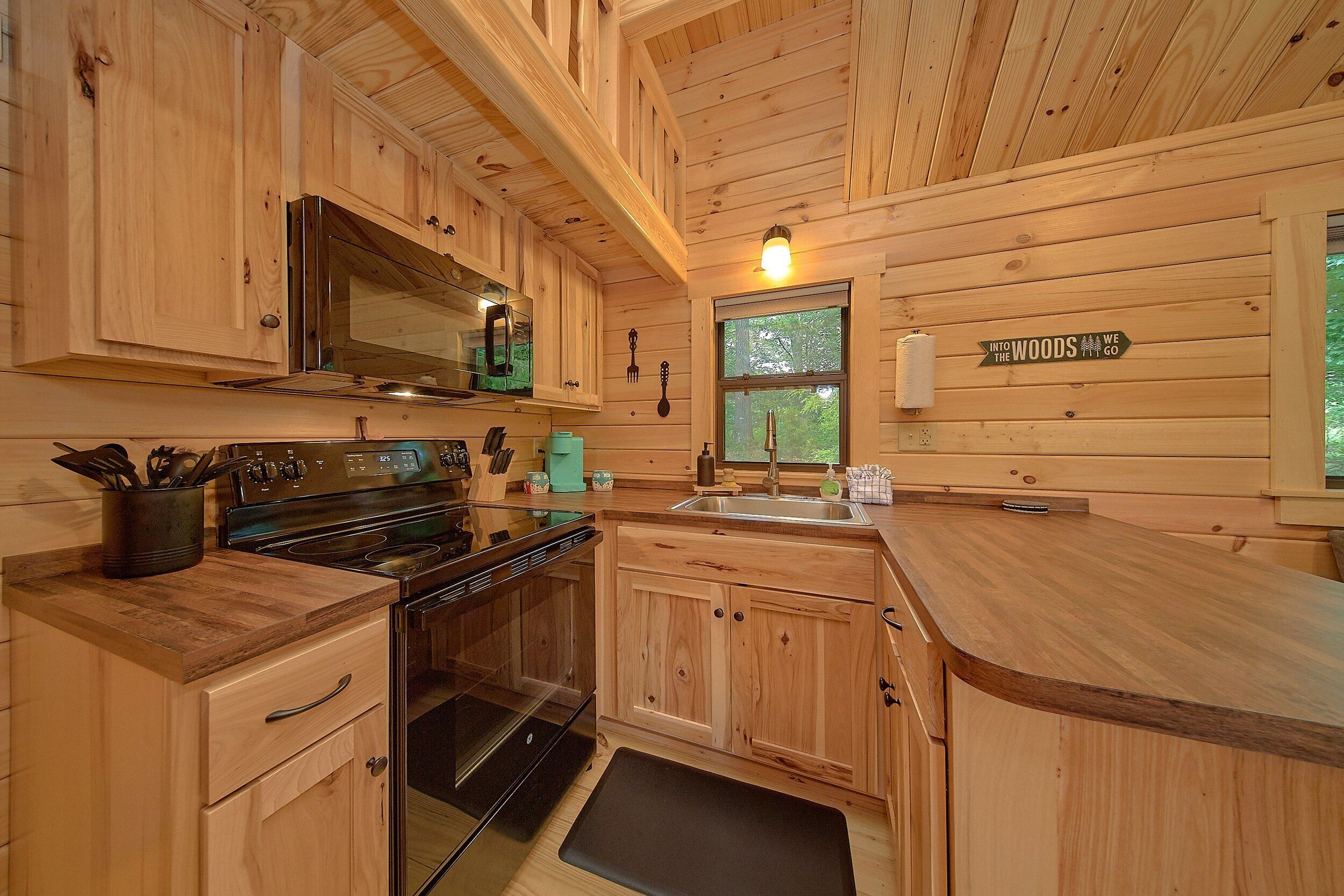 Eine Küchenzeile im Holzblockhaus-Stil mit Mikrowelle, Herd und Spüle.