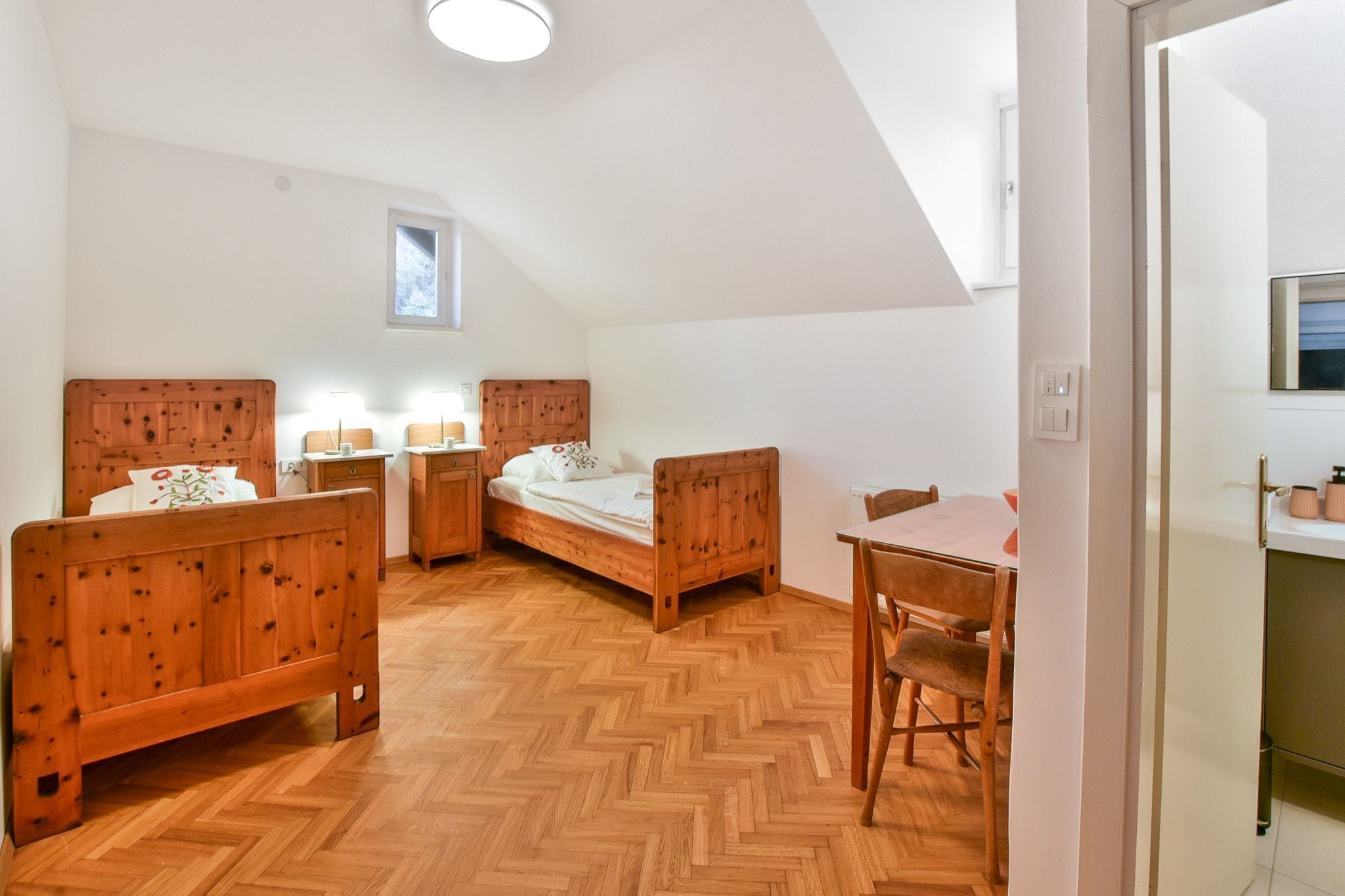 A bedroom with a wooden bed, a wooden nightstand, a wooden desk, and a chair.