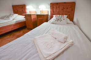 Une chambre d’hôtel avec deux lits en bois, une table de chevet en bois et une lampe de chevet.