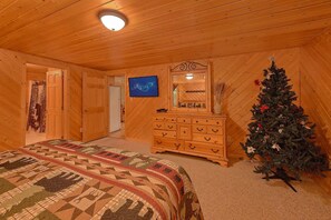 A cozy room with a bed, dresser, and a Christmas tree. - Southern Charm Cabin Rental (Wears Valley)
