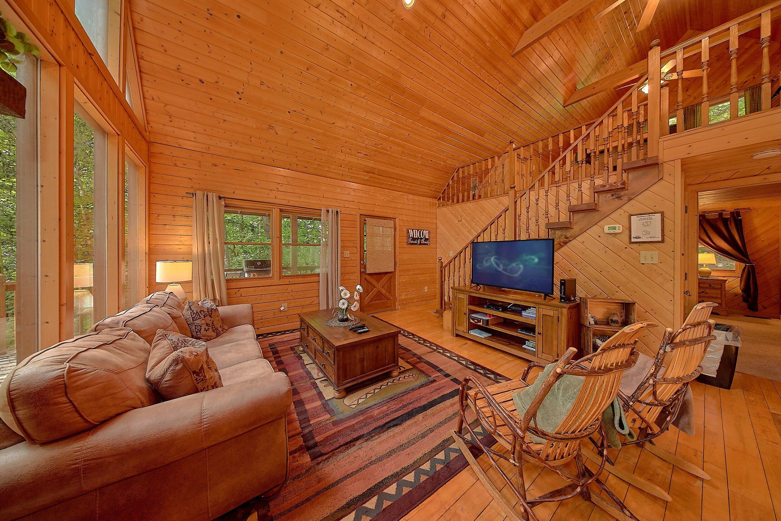 Un interior de madera con sofá, televisor y una escalera.
