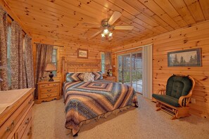 A wooden cabin bedroom with a bed, dresser, chair, and a ceiling fan. - Run to the Hills | Mtn Views, Hot Tub, Resort Pool + Free Attraction Tickets (Wears Valley)