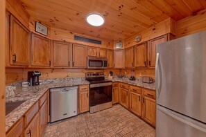 A kitchen with wooden cabinets, a stainless steel refrigerator, a microwave, a stove, and a dishwasher. - Run to the Hills | Mtn Views, Hot Tub, Resort Pool + Free Attraction Tickets (Wears Valley)