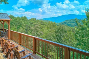 A wooden deck with outdoor seating and a view of a mountainous landscape. - Run to the Hills | Mtn Views, Hot Tub, Resort Pool + Free Attraction Tickets (Wears Valley)