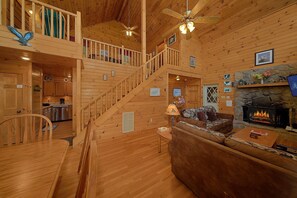 A wooden cabin interior with a staircase, a fireplace, and a dining area. - Eagle's Nest | Mtn Views, Hot Tub, Fireplace + Free Attraction Tickets (Wears Valley)