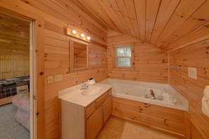 A wooden cabin bathroom with a sink, mirror, and bathtub. - Eagle's Nest | Mtn Views, Hot Tub, Fireplace + Free Attraction Tickets (Wears Valley)