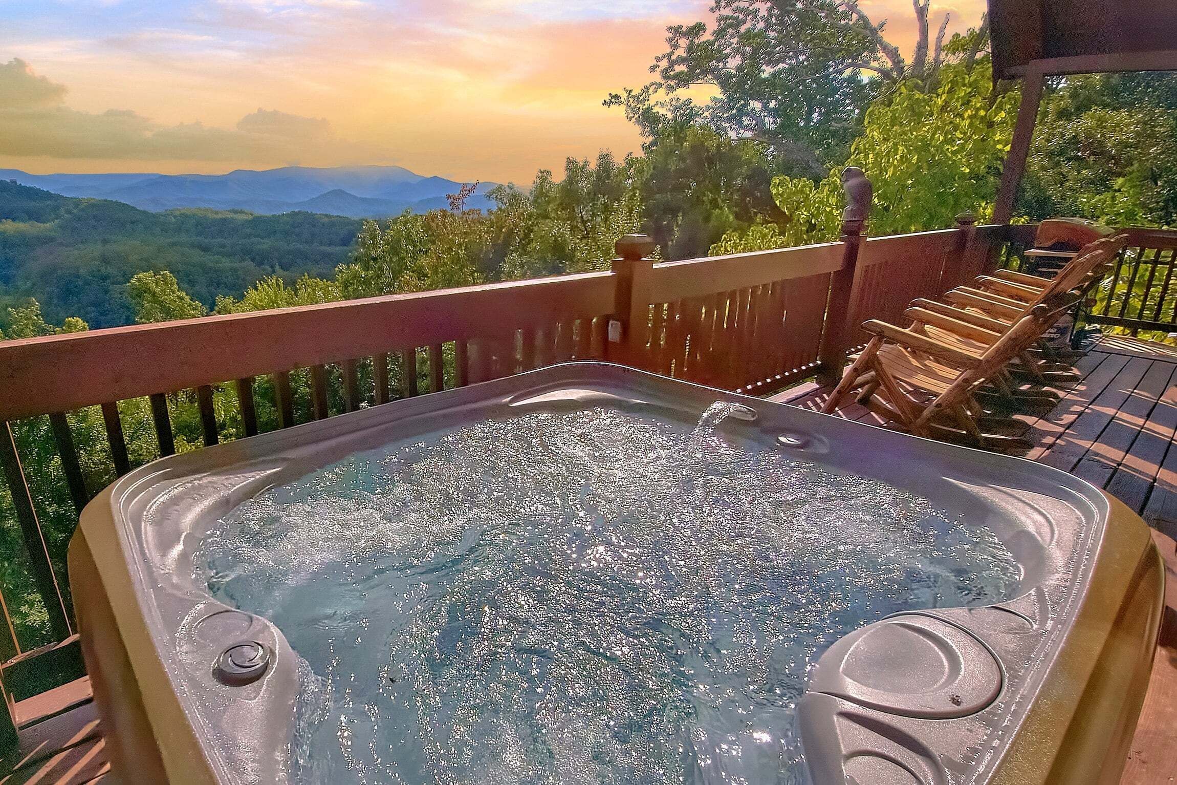Un bain à remous sur une terrasse offrant une vue sur les montagnes et les arbres.