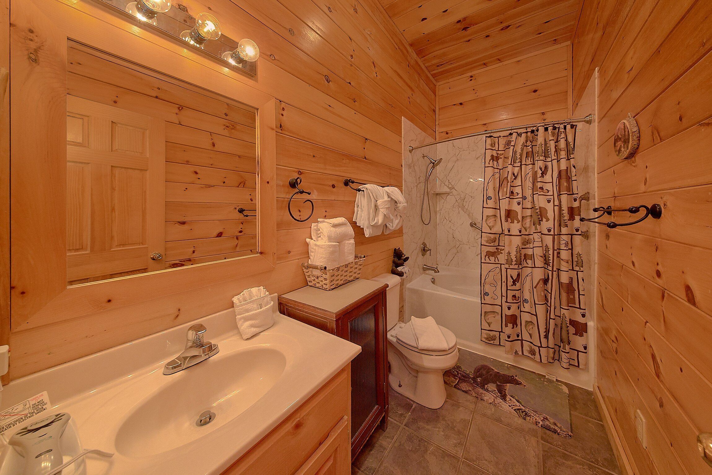 A wooden cabin bathroom with a sink, toilet, and shower.