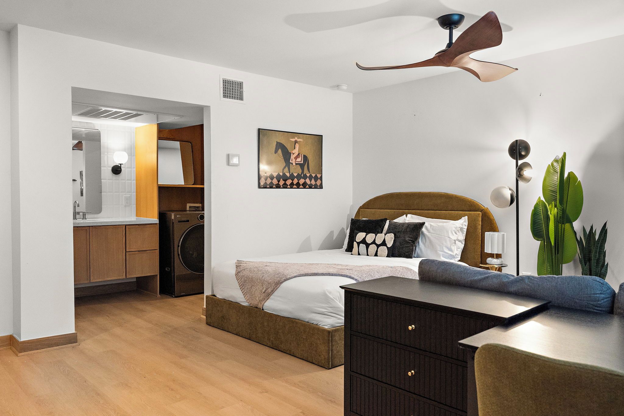 Un dormitorio moderno con cama, mesita de noche, cómoda y ventilador de techo.