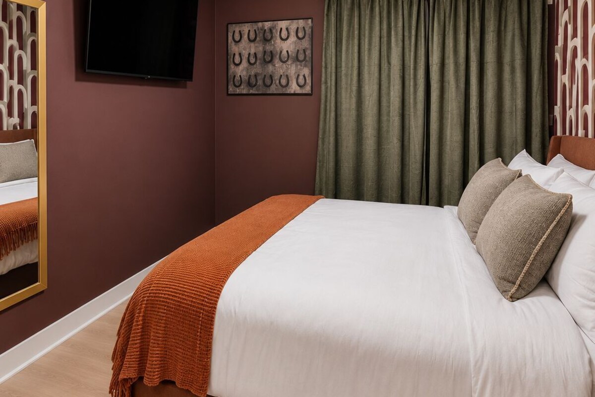 Un dormitorio con una cama grande, un televisor montado en la pared y un adorno decorativo.