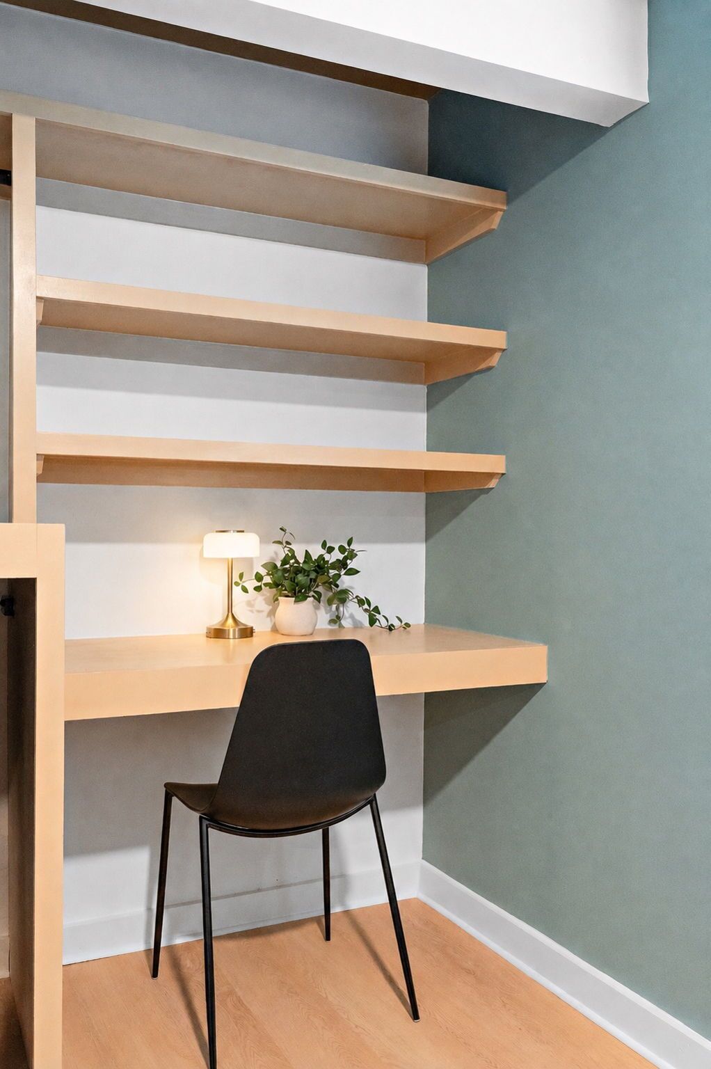 Un rincón de una habitación con una silla negra, un escritorio con una lámpara y una planta en maceta.
