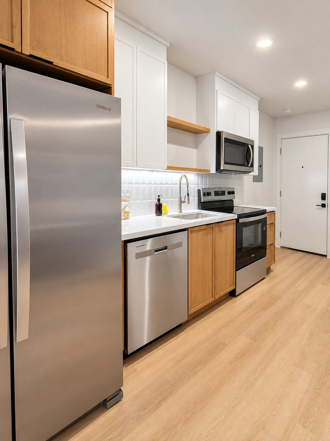 A modern kitchen with stainless steel appliances, wooden cabinets, and a microwave.