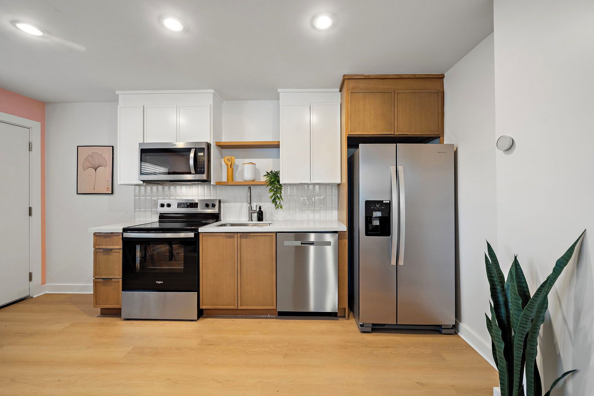 Una cocina moderna con armarios blancos, electrodomésticos de acero inoxidable y suelo de madera.