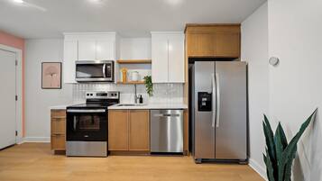 Una cocina moderna con armarios blancos, electrodomésticos de acero inoxidable y suelo de madera.