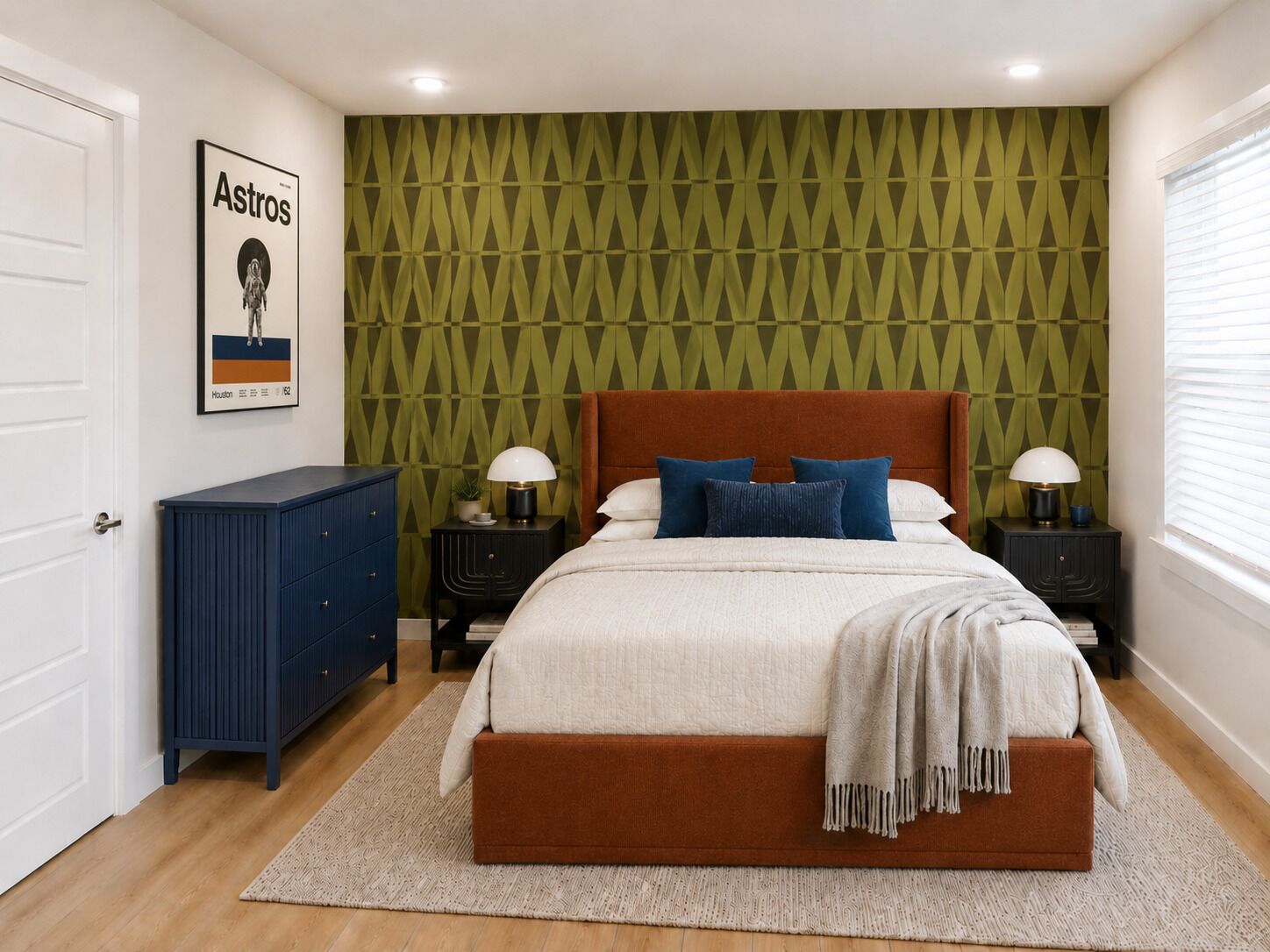 Un dormitorio con cama, mesitas de noche, cómoda y un papel tapiz estampado, además de un cuadro enmarcado.