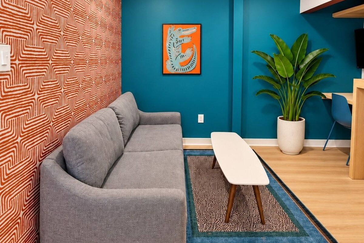 A modern living room with a grey sofa, a white coffee table, a blue accent wall, and a potted plant.