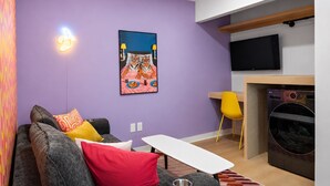 Una sala moderna con un sofá, una mesita, un televisor de pantalla plana y un cuadro en la pared.