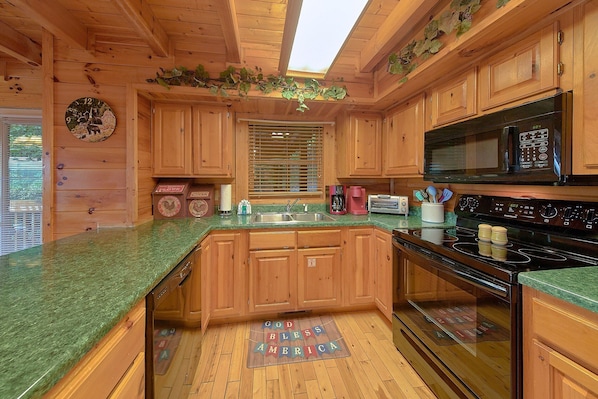 A wooden cabin kitchen with a central island, a microwave, a stove, and a sink.