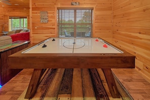 A wooden cabin interior with a foosball table, a window with blinds, and a sign with wildlife-related messages. - Almost Heaven II Cabin Rental (Wears Valley)