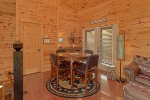 A wooden interior with a dining table, chairs, a sofa, and a sign that reads 'IN EVERYTHING GIVE THANKS'. - Almost Heaven II Cabin Rental (Wears Valley)