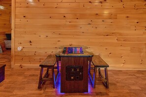 A wooden wall with a table and benches, a digital device on the table, and a power outlet on the wall. - Almost Heaven II Cabin Rental (Wears Valley)