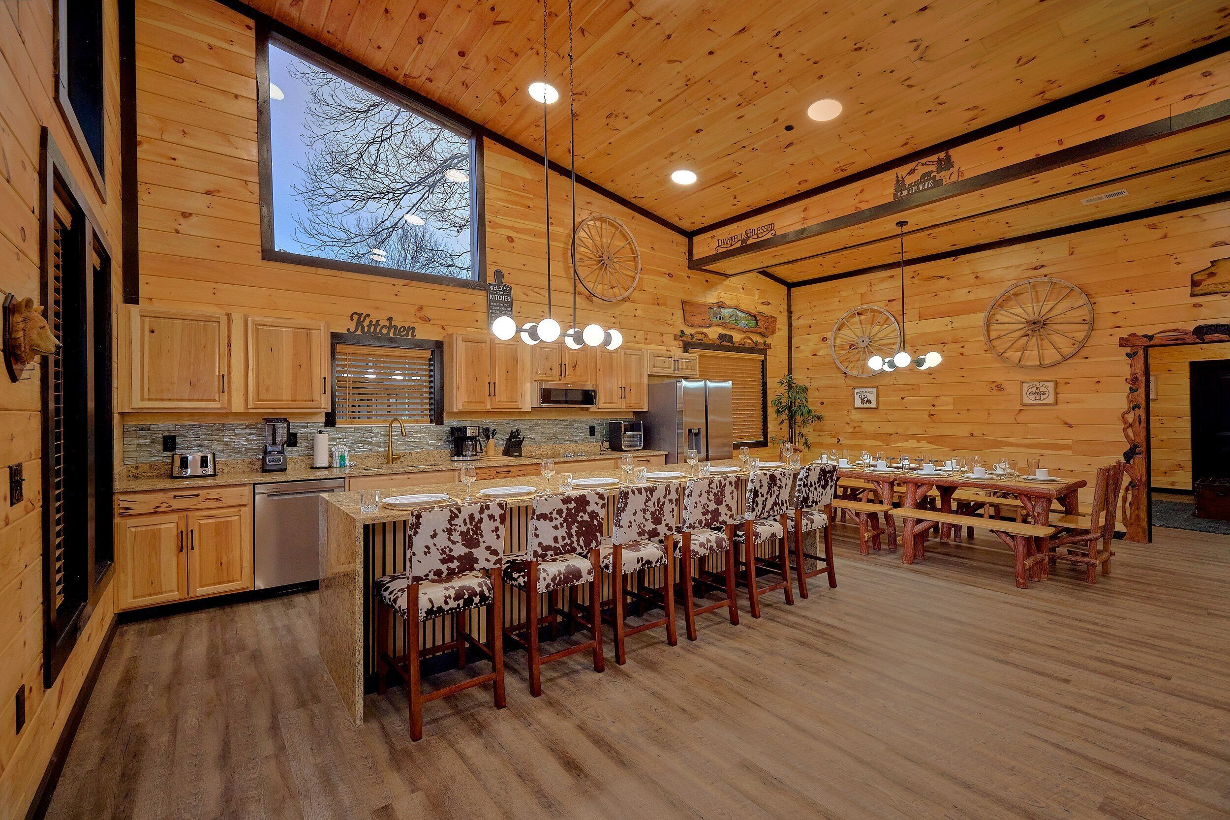 A rustic wooden interior with a kitchen, dining area, and a large window.