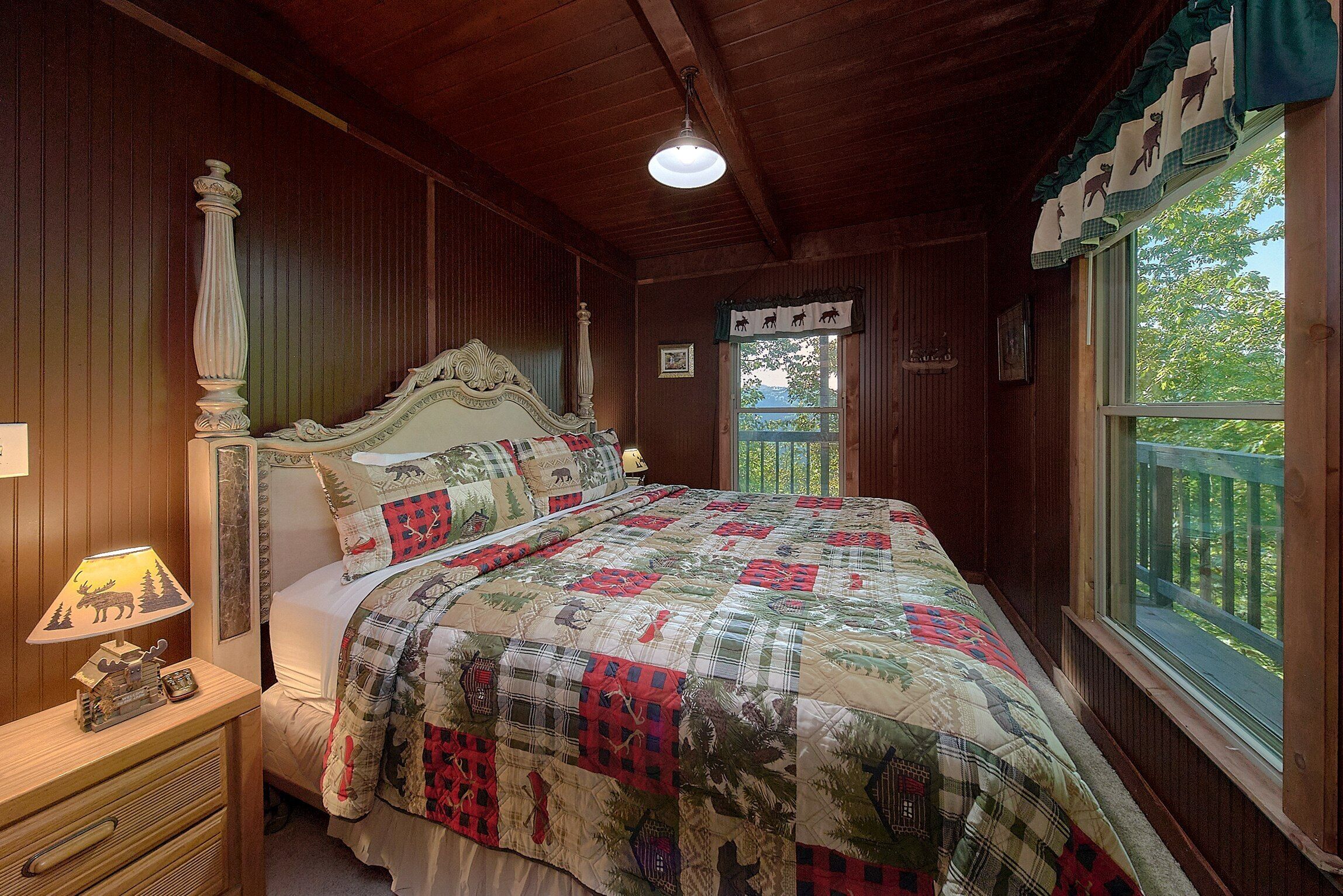 Une chambre à coucher aux murs lambrissés, avec un lit à baldaquin, une table de chevet dotée d’une lampe et une fenêtre donnant sur un paysage verdoyant.