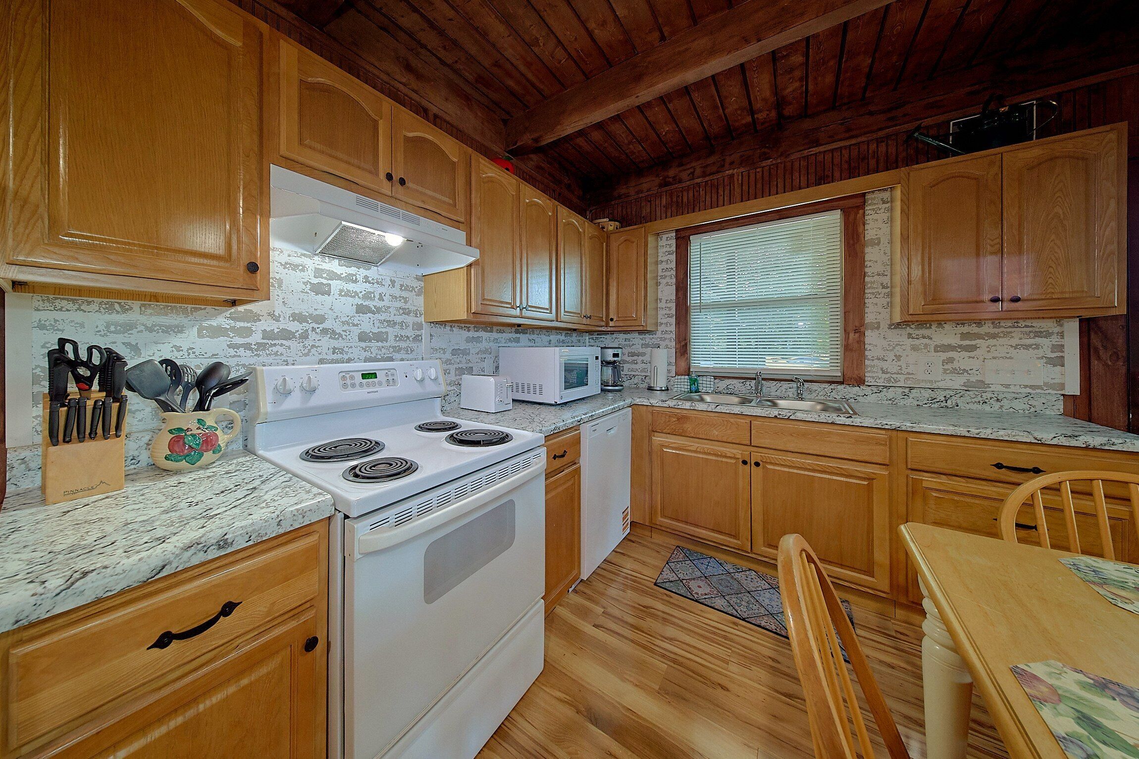 A kitchen with wooden cabinets, a white stove, a microwave, and a sink.