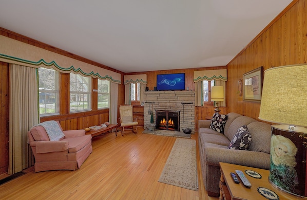 Una sala de estar acogedora con chimenea, paredes de madera y televisor.
