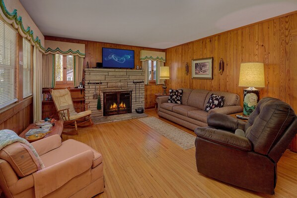 A cozy living room with a fireplace, a television mounted above it, and a comfortable seating area with a sofa and chairs. - Aspen House Walk to Downtown Gatlinburg River View + Free Attraction Tickets (Gatlinburg)