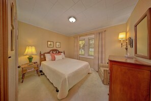 Een hotelkamer met een bed, nachtkastje, lamp en een kaptafel met spiegel.